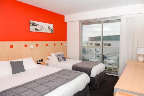 莱萨布勒-多洛讷Kyriad Prestige Les Sables d'Olonne - Plage - Centre des Congrès的橙色墙壁的酒店客房内的两张床