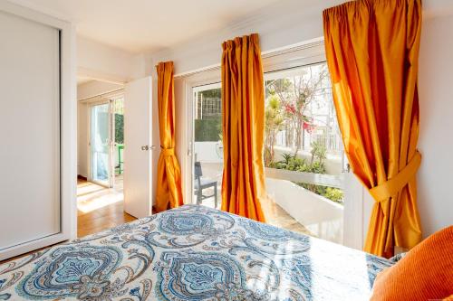 阿德耶Royal Park Torviscas Beach的一间卧室配有橙色窗帘和一张床,并设有一个阳台