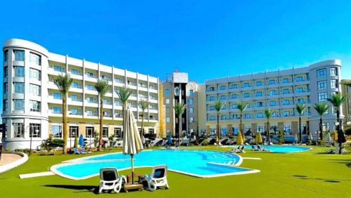 开罗Jewel Sport City and Aqua Park的一座带大型游泳池的度假村,位于一座建筑前