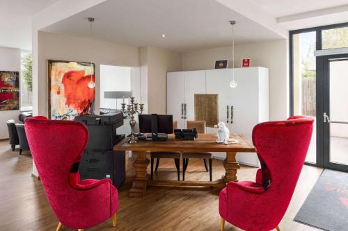 格拉茨Amedia Luxury Suites Graz, Trademark Collection by Wyndham的一间带木桌和红色椅子的用餐室