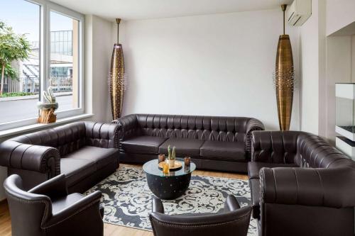 格拉茨Amedia Luxury Suites Graz, Trademark Collection by Wyndham的客厅配有真皮沙发和椅子