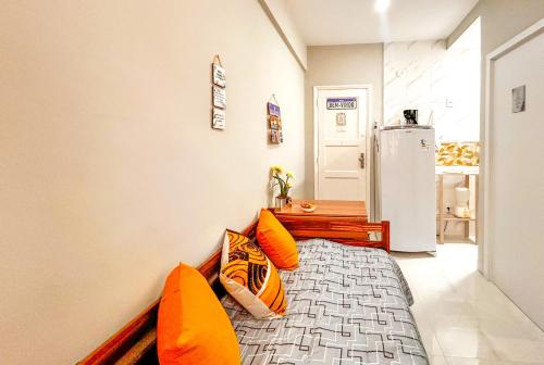里约热内卢Ótimo studio c WiFi a 190m da Praia do Leme - RJ的一间卧室配有一张带橙色枕头的床和一台冰箱