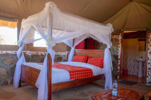 马赛马拉Orng'atuny Mara King Camp的一间帐篷内带天蓬床的卧室