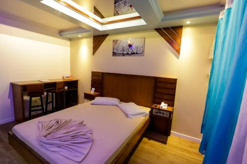 格拉玛多阿维尼达汽车旅馆（仅限成人入住）的一间卧室配有一张带紫色床单的床和一张书桌。
