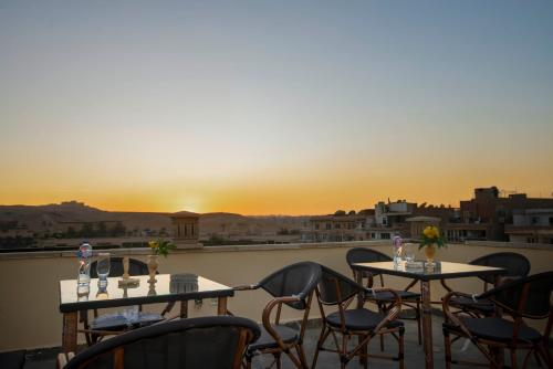开罗King Pyramids View Hotel的阳台上配有两张桌子和椅子,享有日落美景