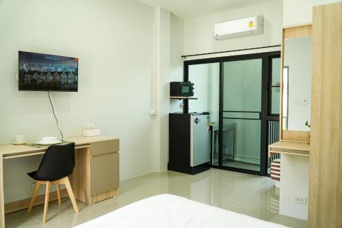 Ban Dam Phraเมตตา เรสซิเด้นซ์ - Metta Residence的客房设有冰箱、书桌和椅子。