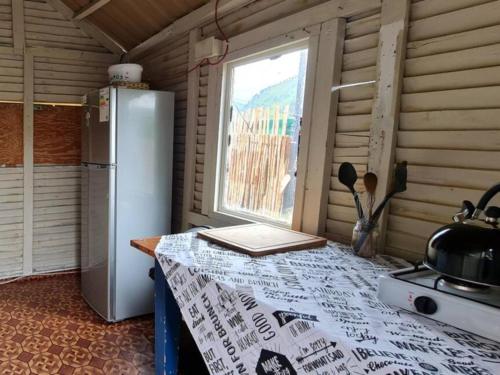StormsriviermondTsitsikamma Wolf Sanctuary ECO Cabins & Teepees的厨房配有桌子、冰箱和窗户。