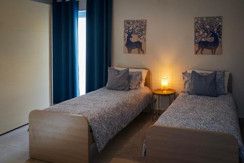 圣保罗湾城Comfort and Convenience flat 4 dad's court的配有蓝色窗帘和窗户的客房内的两张床