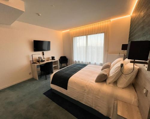 普雷兰LE MANOIR DU ROSELIER HOTEL 3 étoiles的一间卧室配有一张带书桌的床和窗户。