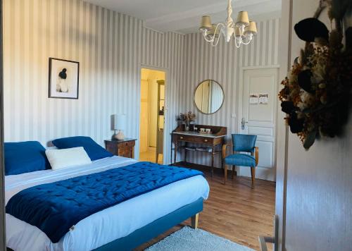 Au fil de L'Ouanne的一间卧室配有蓝色的床、一张书桌和镜子