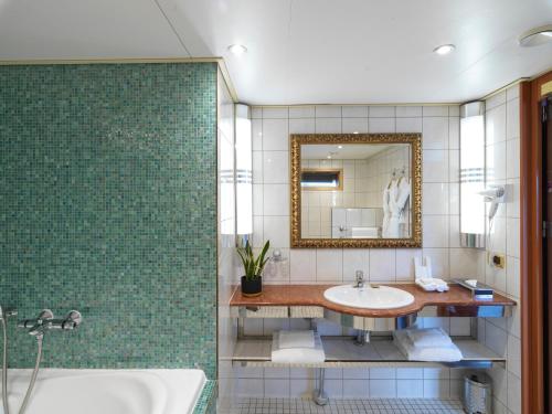 伦敦森伯恩伦敦帆船酒店的浴室配有盥洗盆、镜子和浴缸