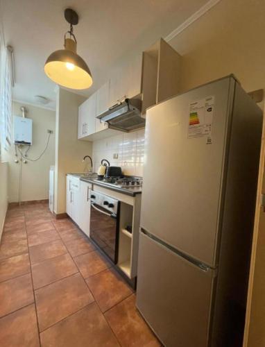 库里科Depto para 2 a 4 personas的厨房配有不锈钢冰箱和白色橱柜