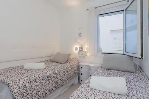 桑帕克Peaceful Flat Menorca Sea And Wifi的一间白色卧室,配有两张床和窗户