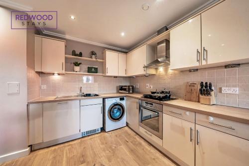 沃金Spacious 2 Bed 2 Bath Apartment, Near Train Station, FREE Parking By REDWOOD STAYS的厨房配有白色橱柜和洗碗机。
