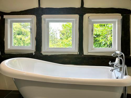 阿伯利The Manor at Abberley的带浴缸的浴室和2个窗户