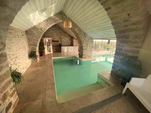 Saint-BeauzélyLes Caselles, Gîte et Maison d'hôtes的一座带拱门的房子中的室内游泳池