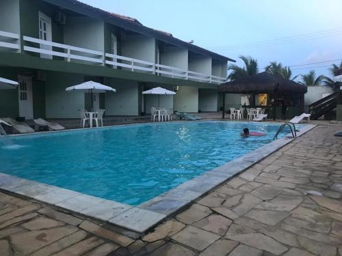 阿尔科巴萨Hotel Convés do Farol的在建筑物旁边的游泳池游泳的人