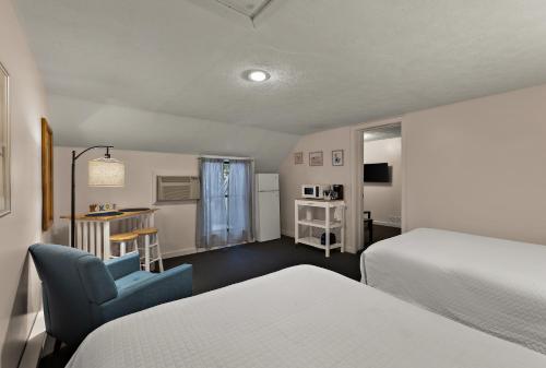 特拉弗斯城特拉弗斯湾宾馆的酒店客房,设有两张床和一张蓝色椅子
