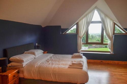 CloneenThe Mountain Lodge Slievenamon spacious 4 bedroom house的一间卧室设有一张大床和两个窗户