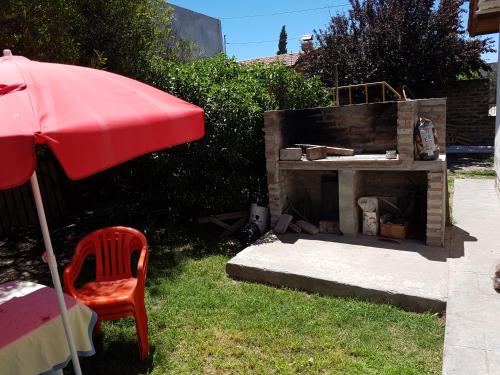 别德马Casa con pileta "CACHAPATAGONICA" calle Junin 1877的砖砌壁炉,配有红伞和椅子