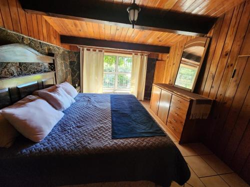 Cerro de OroCASA XOCOMIL的一间带一张大床的卧室,位于带木墙的房间