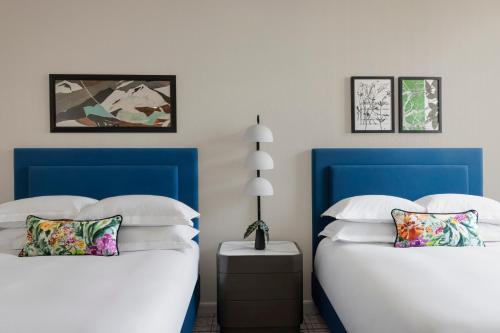 盐湖城摩纳哥盐湖城金普顿酒店的客房内的两张床和蓝色床头板