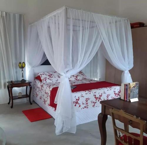 蒙蒂达斯加梅莱拉斯Chalé romântico, com vista panorâmica, para Casais的一间卧室配有一张带白色窗帘和桌子的床