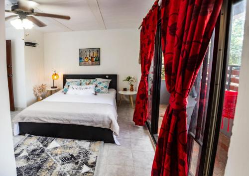 伊瓦格Coliving7 Aparta Hotel & Habitaciones的一间卧室配有床和红色窗帘