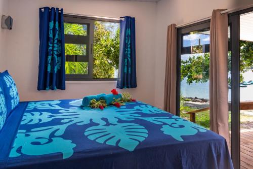 波拉波拉Matira Beach Raitea 1的一间卧室配有一张带鲜花的蓝色床