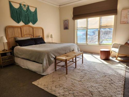墨尔本Hillcrest Harmony: Luxury in Westmeadows 20% OFF的一间卧室配有一张大床、一把椅子和窗户。