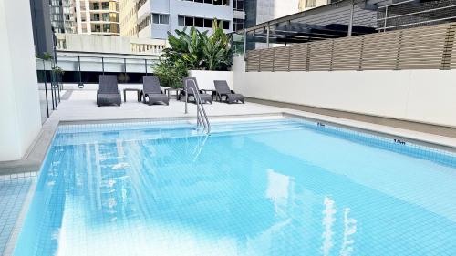 布里斯班Oaks Brisbane on Charlotte Suites的一座带椅子的大型游泳池和一座建筑