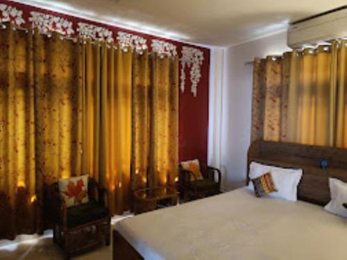 古瓦哈提Mulberry Guesthouse Guwahati的一间卧室配有床、窗帘和椅子