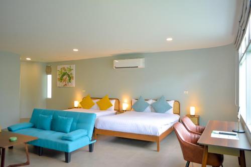 班泰神曲海滩度假酒店的一间卧室配有两张床和蓝色的沙发