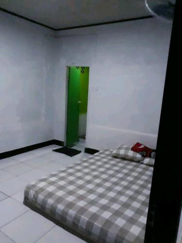 CikadalPenginapan & Homestay Geopark Ciletuh的一间设有一张床铺的卧室,位于带绿门的房间