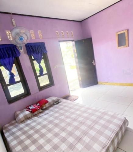 CikadalPenginapan & Homestay Geopark Ciletuh的紫色客房内的一间卧室,配有一张床