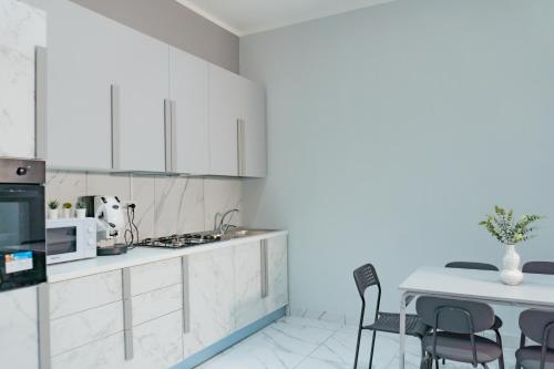 那不勒斯Hostel Partenope的厨房配有白色橱柜和桌椅