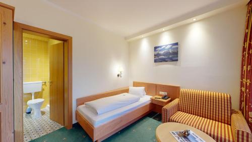 瓦德林Hotel Tiroler Adler Bed & Breakfast的一间卧室配有一张床、一张沙发和一张桌子