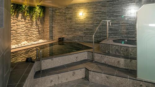 花卷市Hotel Grand Ciel Hanamaki的砖墙房间内的热水浴缸