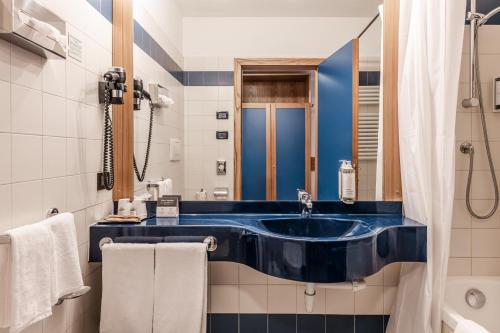 迪马罗Hotel garni Meledrio的浴室配有蓝色水槽和淋浴。