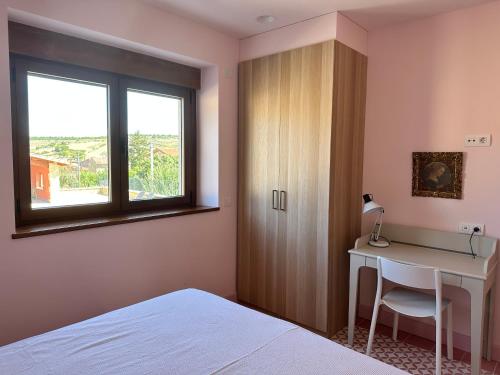 布尔戈斯La Casa Rosa的一间卧室配有书桌、床和窗户。