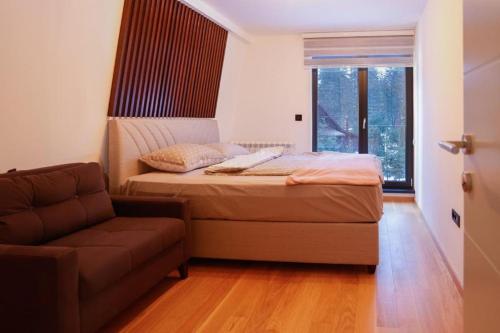 亚霍里纳Winter House TT Jahorina的一间卧室配有一张床、一张沙发和一个窗口