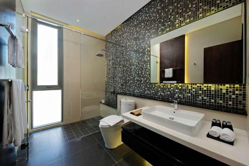 岘港Deluxe Beach Villas by Danatrip的一间带水槽、卫生间和镜子的浴室
