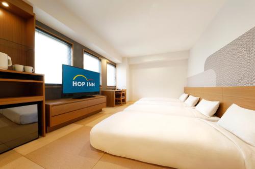 京都Hop Inn Kyoto Shijo Omiya的酒店客房设有两张床和一台平面电视。