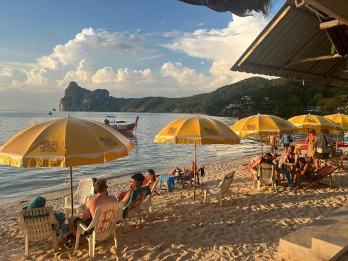 皮皮岛Phi Phi Ocean Club的一群人坐在海滩上,拿着遮阳伞
