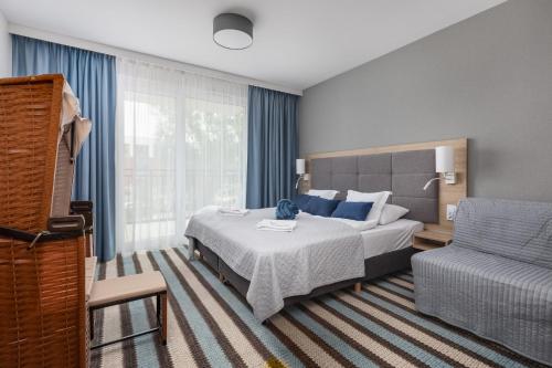 米兹多洛杰Sunny Apartments in Bel Mare Resort by Renters的一间卧室配有一张床、一张沙发和一把椅子