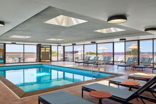 马斯基根Delta Hotels by Marriott Muskegon Convention Center的游泳池设有桌椅和窗户