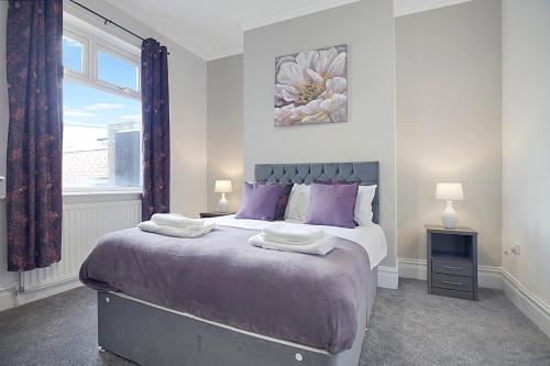毕晓普奥克兰Spacious Retreat with Backyard Bliss, Sleeps 7的一间卧室配有一张带紫色枕头的床和窗户。