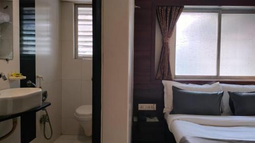 纳威孟买Hotel Sai Nidhi Executive-MindSpace Airoli Navi Mumbai的浴室设有床、水槽和窗户。