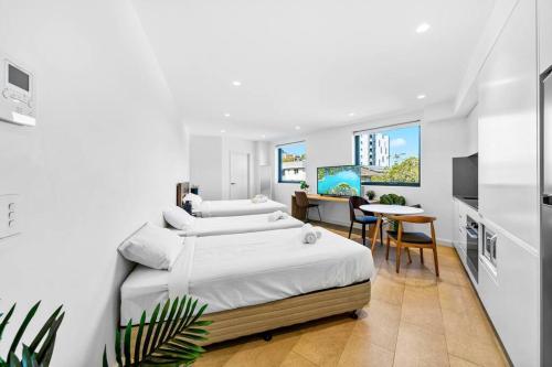 悉尼Lovely Studio apartments in Strathfield CBD的白色卧室配有两张床和一张桌子