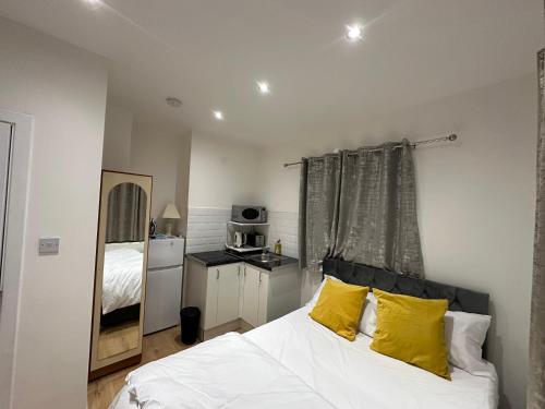 布罗姆利1st Studio Flat With full Private Toilet And Shower With its Own Kitchenette in Keedonwood Road Bromley A Fully Equipped Independent Studio Flat的一间卧室配有白色床和黄色枕头